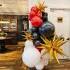 Red, white, and graphite balloon installation with giant gold foil stars by Just Peachy for a dispensary opening in Little Rock.