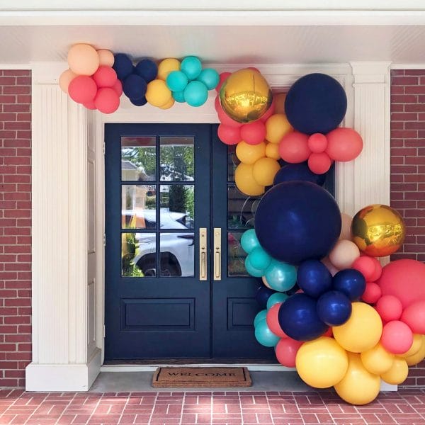 Balloon arch over doorway with navy, teal, coral, and yellow balloons by Just Peachy in Little Rock, Arkansas.