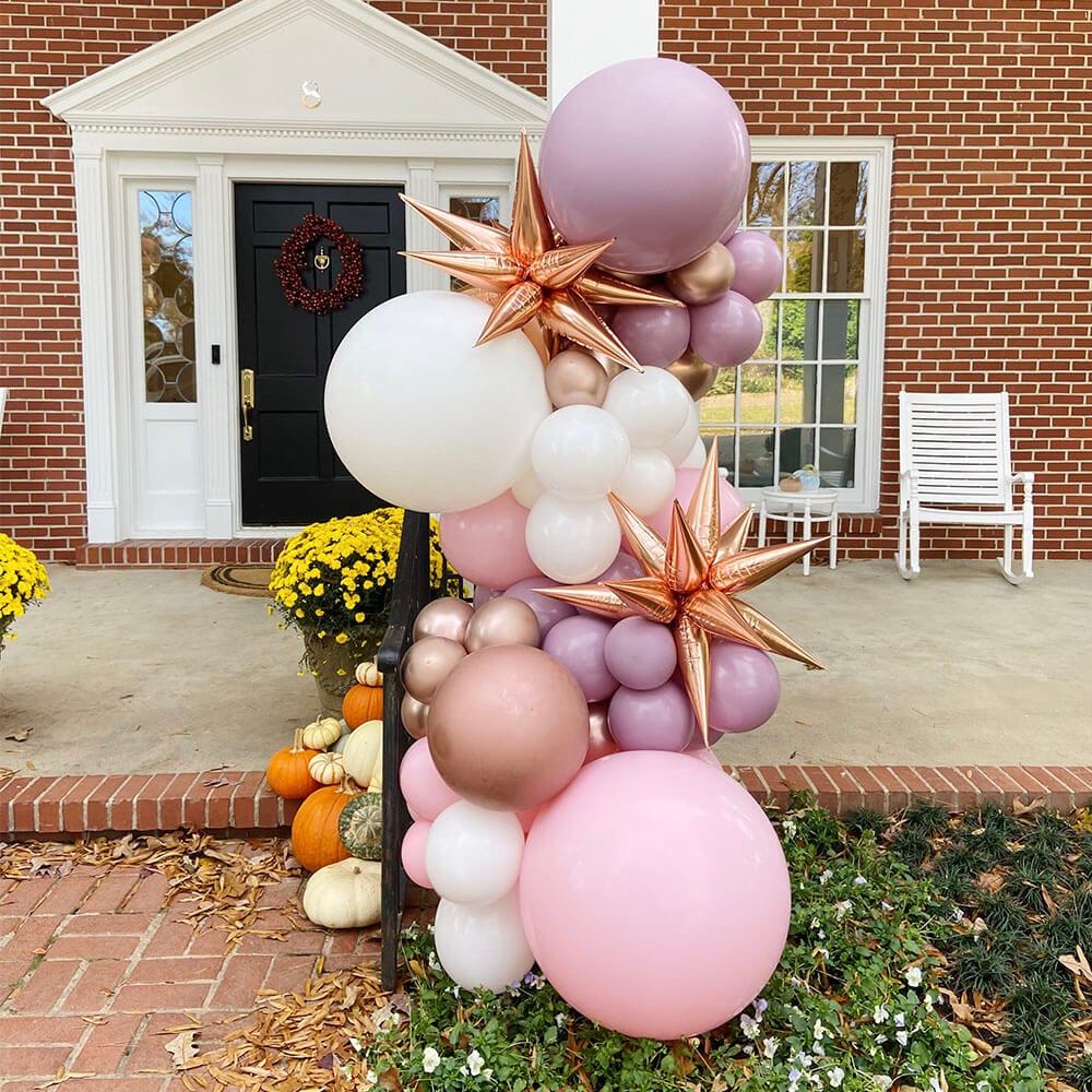 Gorgeous lavender, pink, and rose gold vertical balloon garland installation outside of a home in central Arkansas by Just Peachy.