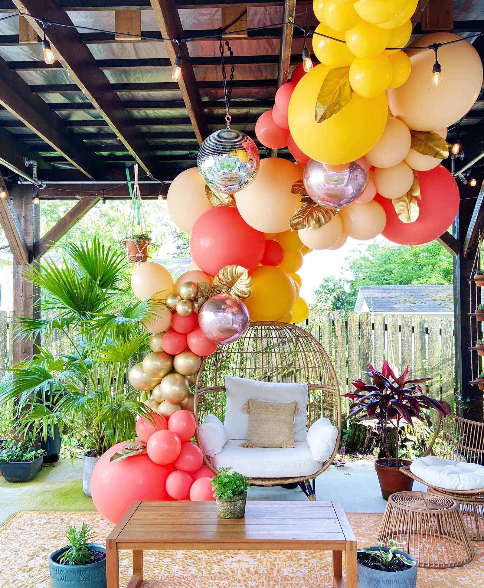 Just Peachy custom color wedding shower balloon arch install over round wicker chair with coral, white, peach, goldenrod and rose gold metallic balloons in central Arkansas.