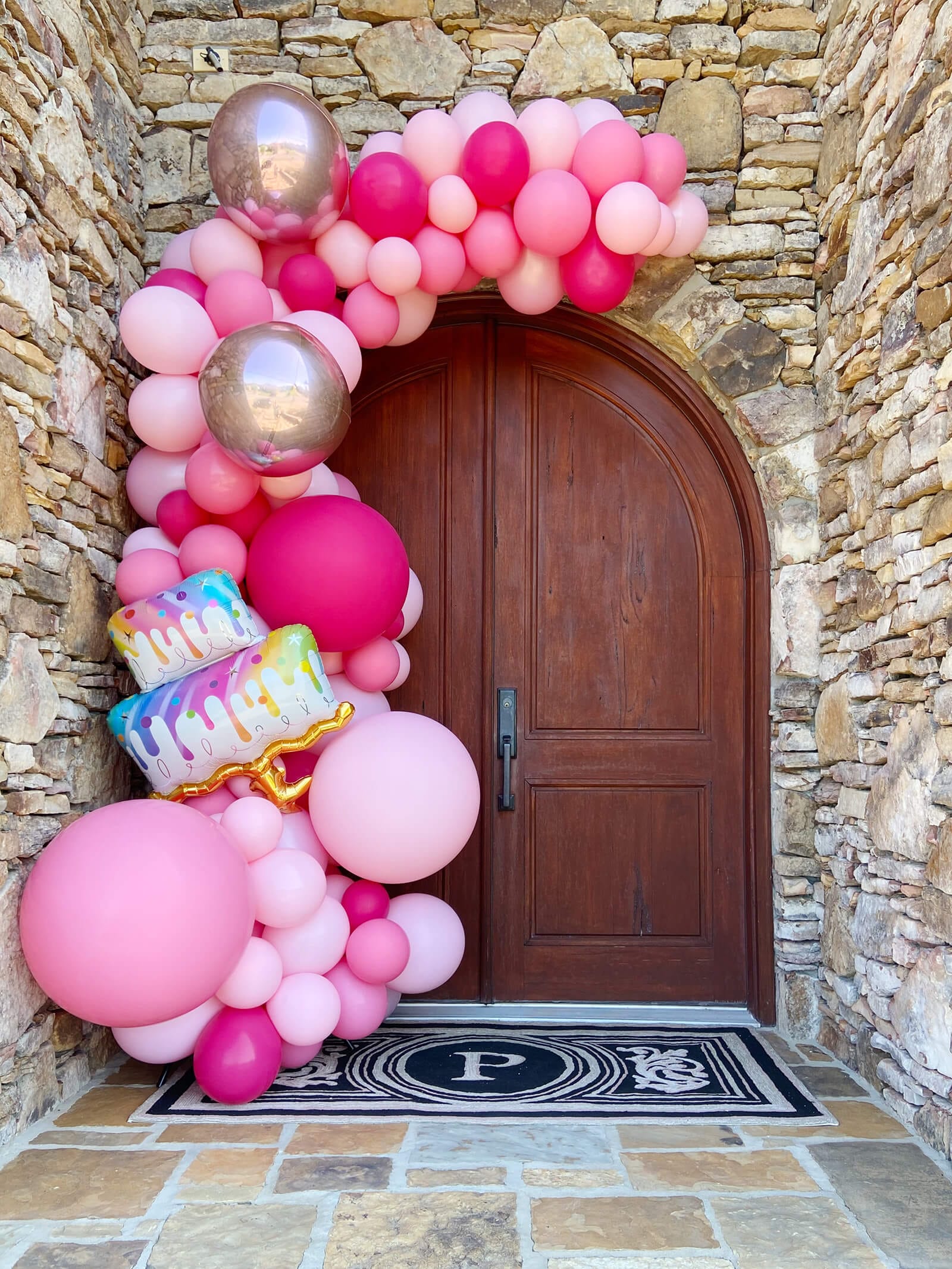 Pink and silver happy birthday balloons arch over a front door in Little Rock, Arkansas.