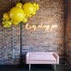 Image of pink couch in front of a brick wall with neon overhead reading “it was always you,” rental available from Just Peachy in Little Rock.