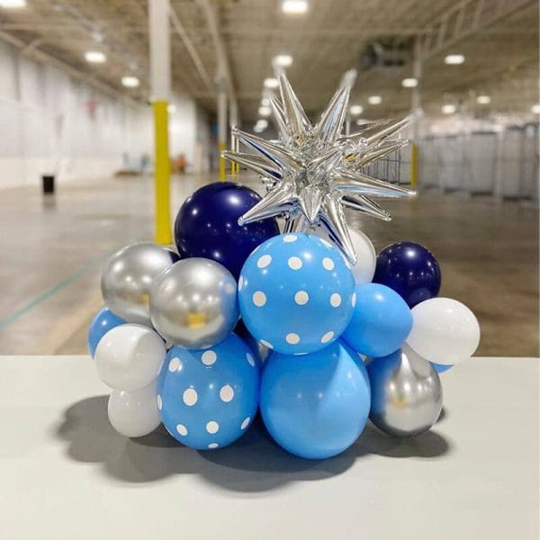 Blue, silver and white balloons with a silver star make a tabletop for events available at Just Peachy.