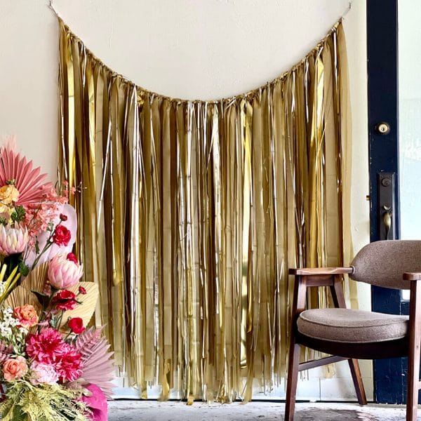Streamer garland with shades of matte and shiny chrome gold makes a beautiful party wall decoration or event photo backdrop available from Just Peachy in Little Rock.