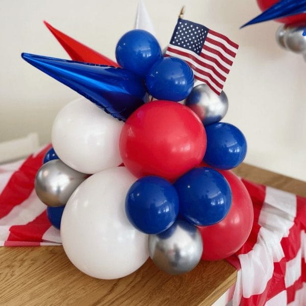 Bright red, white and blue balloons, a tiny American flag, and starburst Tabletopper from Just Peachy for the 4th of July.